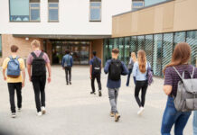 Rear View Of High School Students Walking Into College Building Together